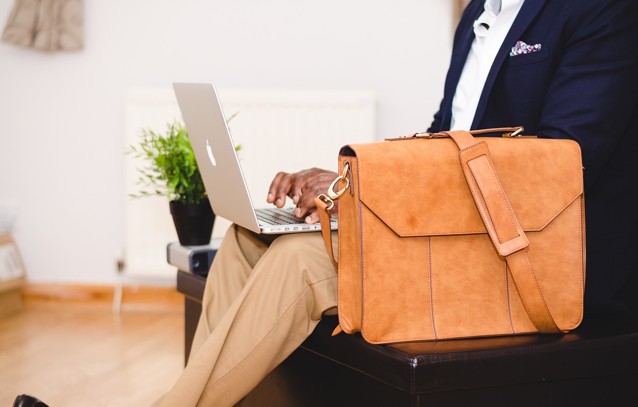 business man working on laptop with bag in front of him